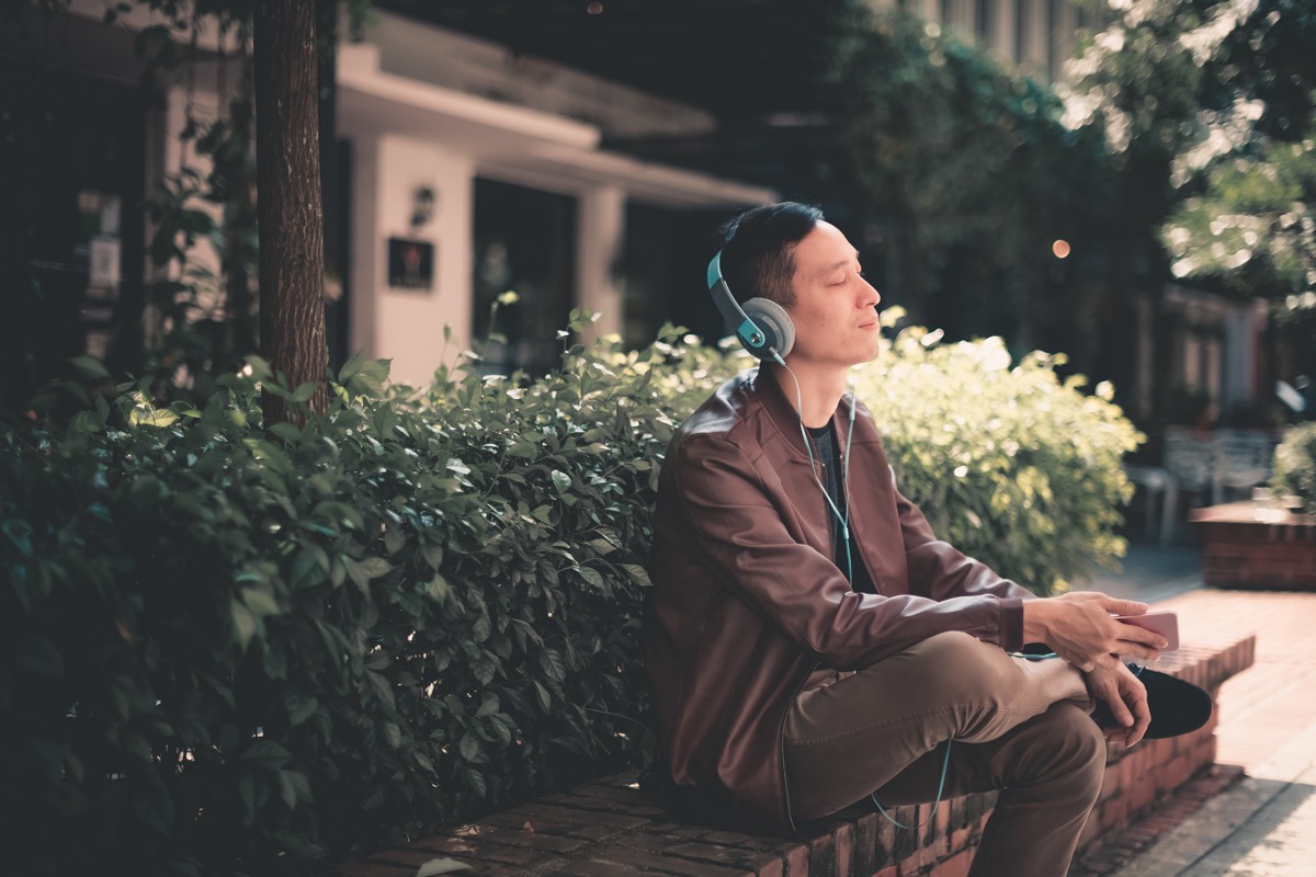young asian chinese male sitting down and listening to music