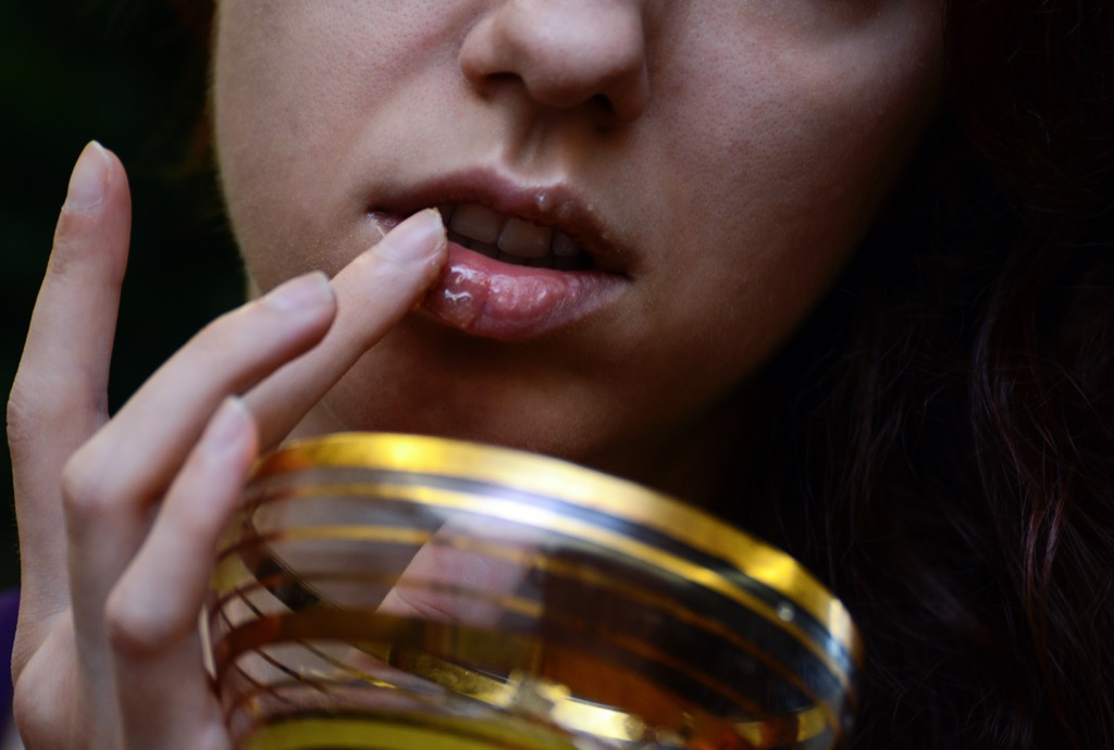 a woman applying olive oil to her lips