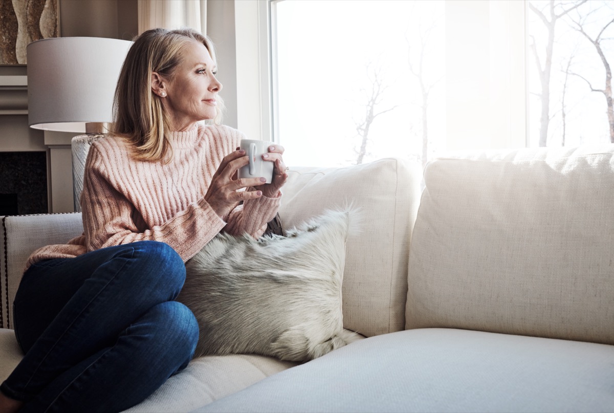 woman sitting alone on the couch sipping coffee