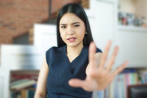 Asian woman putting her hand up and saying no
