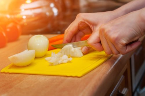 chopping onions on a plastic cutting board things you should clean every day