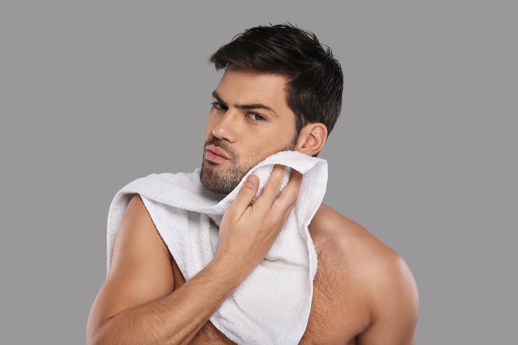 man rubbing face with a towel