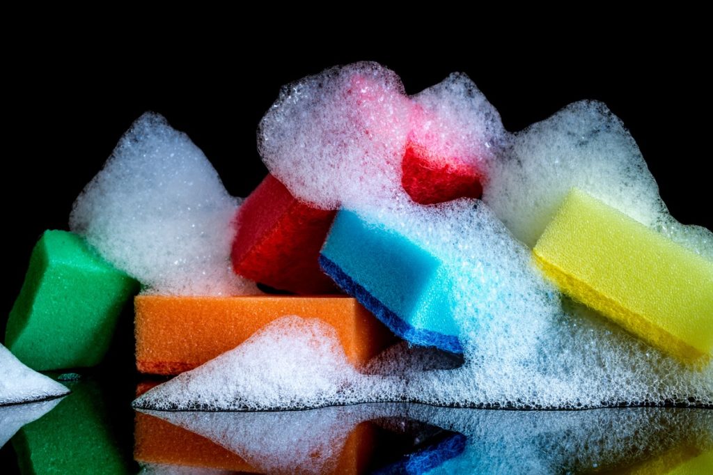 Colorful sponges with foam and reflection isolated on black background