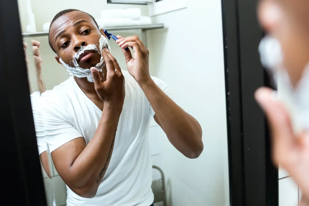black man shaving in the mirror