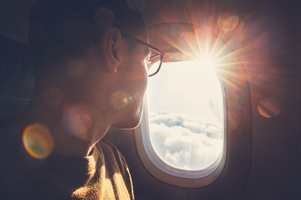 man in glasses looks out an airplane window