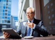 an older businessman ponders retirement while looking at an ipad, office etiquette