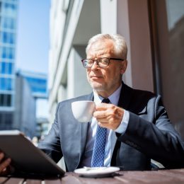 an older businessman ponders retirement while looking at an ipad, office etiquette