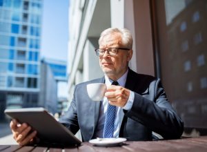 an older businessman ponders retirement while looking at an ipad, office etiquette