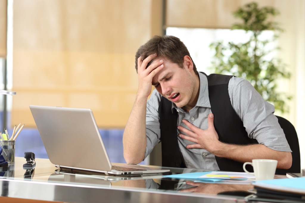 Man suffering from a panic attack at work under stress {physical effects of stress}