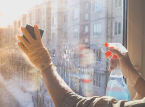 person cleaning a glass window, easy home tips