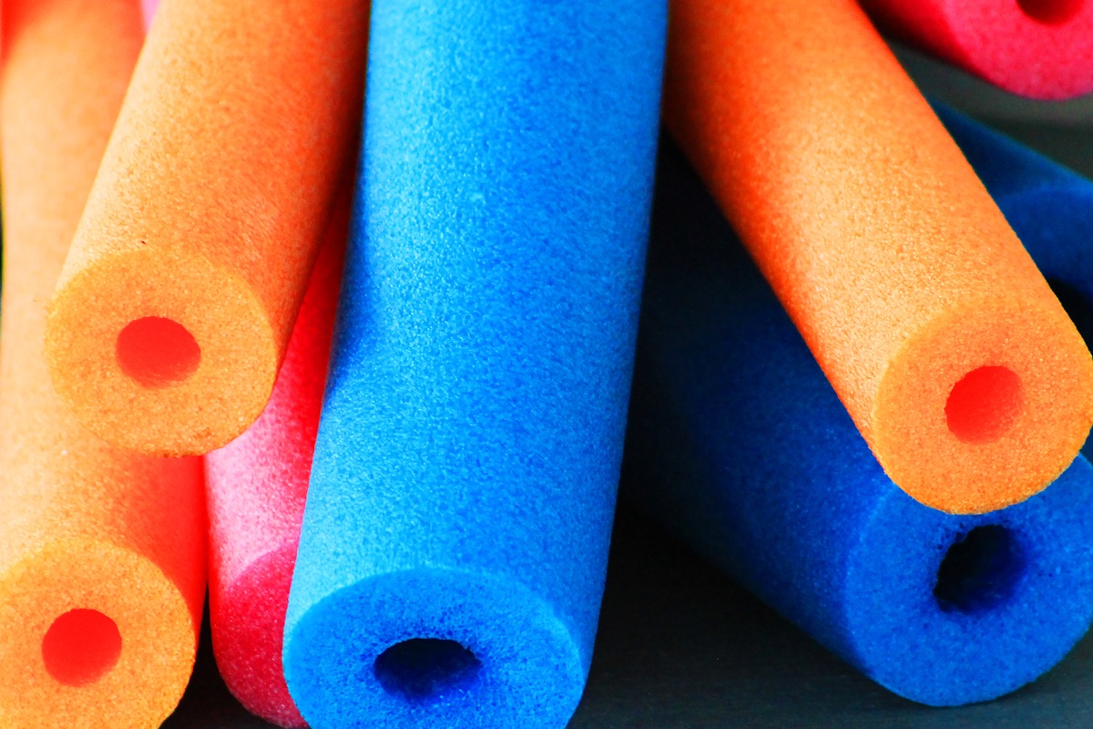 Close-up of colorful pool noodles, end view looking along noodles.
