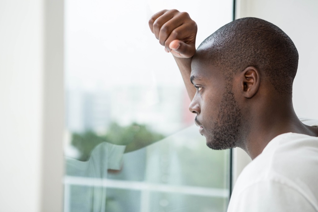 sad black man stares out window