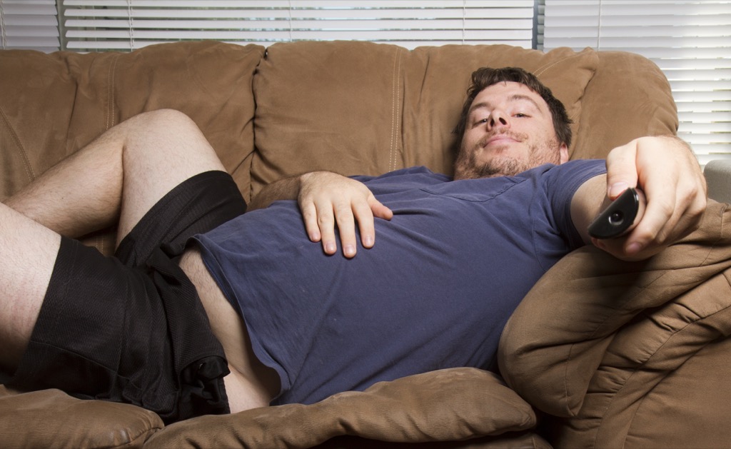 man laying on couch watching tv