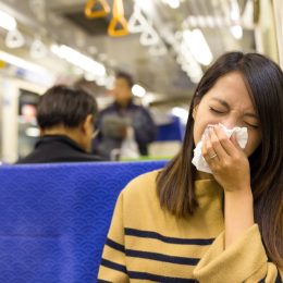 woman sick and sneezing on the bus