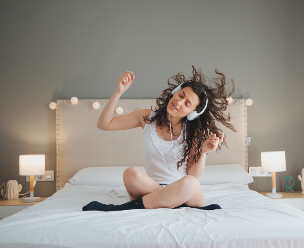 woman listening to music with headphones in bed