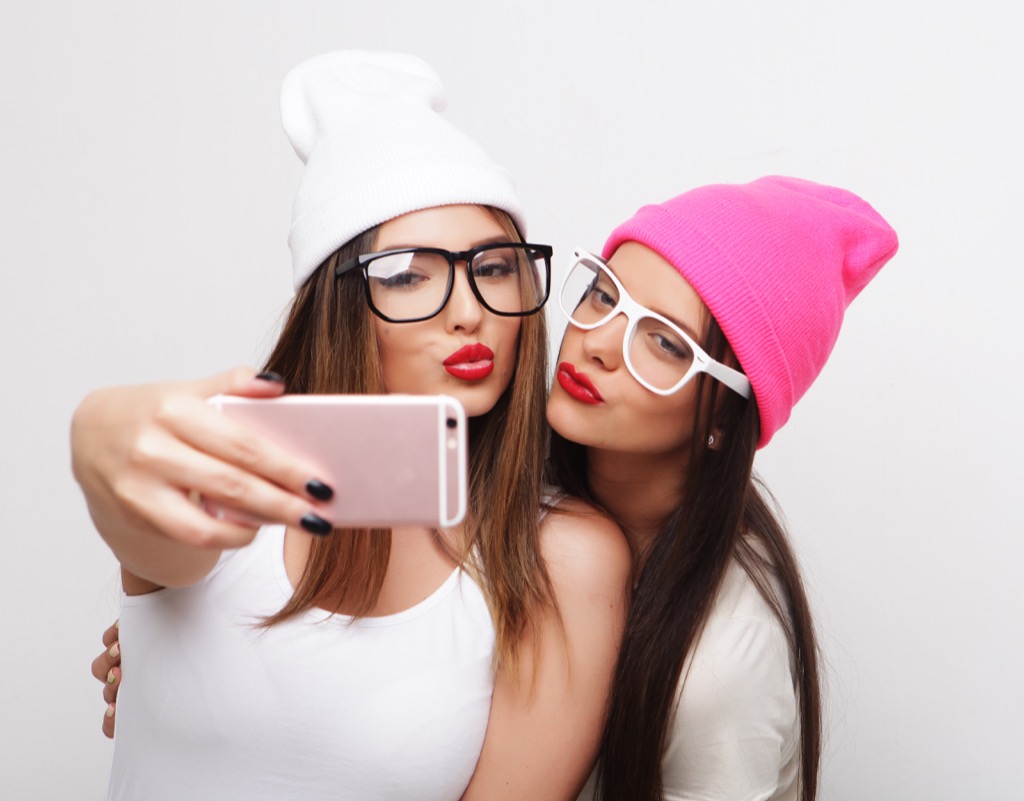 teens wear silly glasses and beanie hats and take selfie
