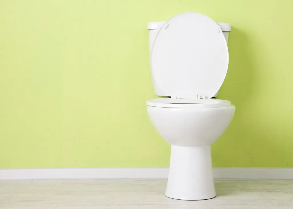 toilet against a lime green wall background