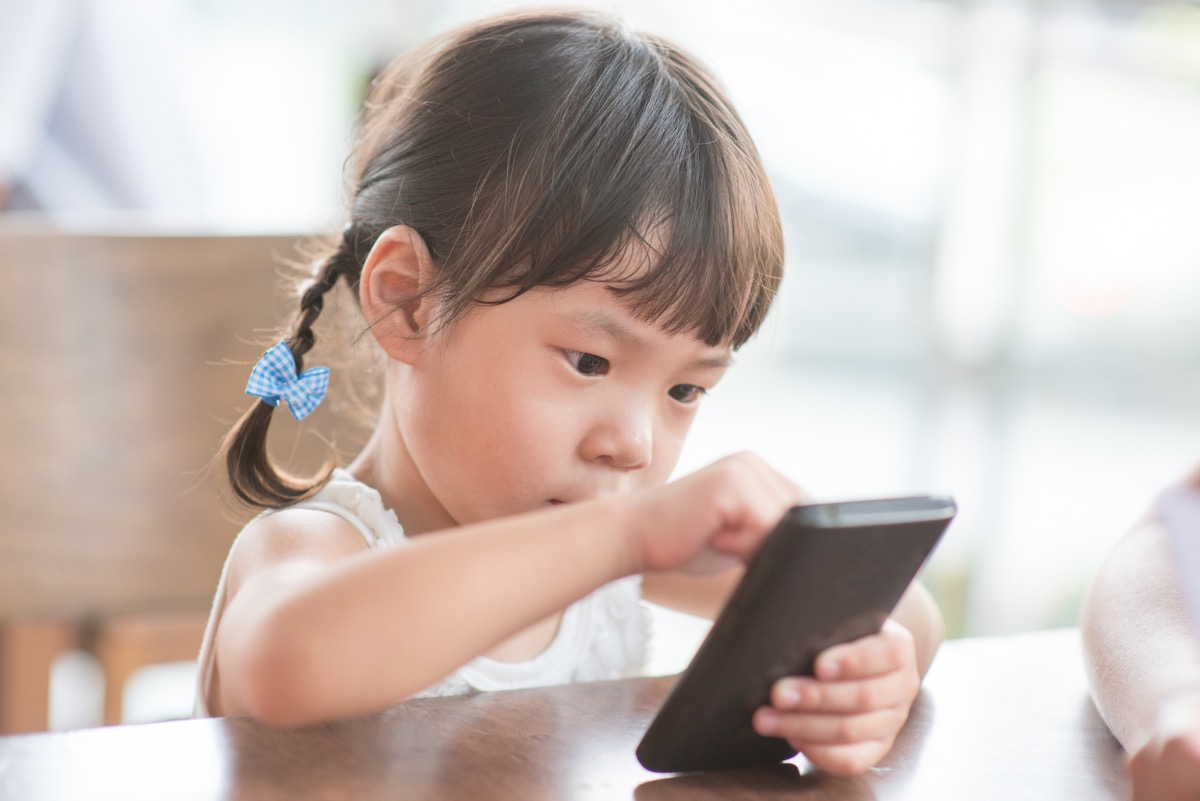 a young girl playing with a smartphone