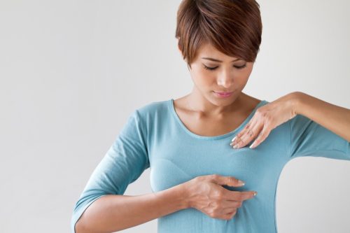 woman checking breast, subtle symptoms of serious disease
