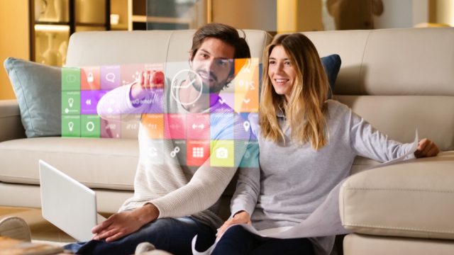 couple sitting on a sofa playing with augmented reality smart home settings