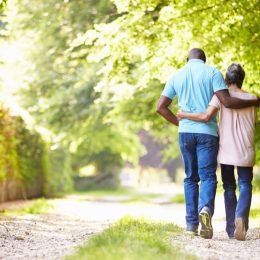 couple walking down a sunny wooded path