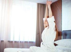Happy woman in bed who loves Daylight Saving Time