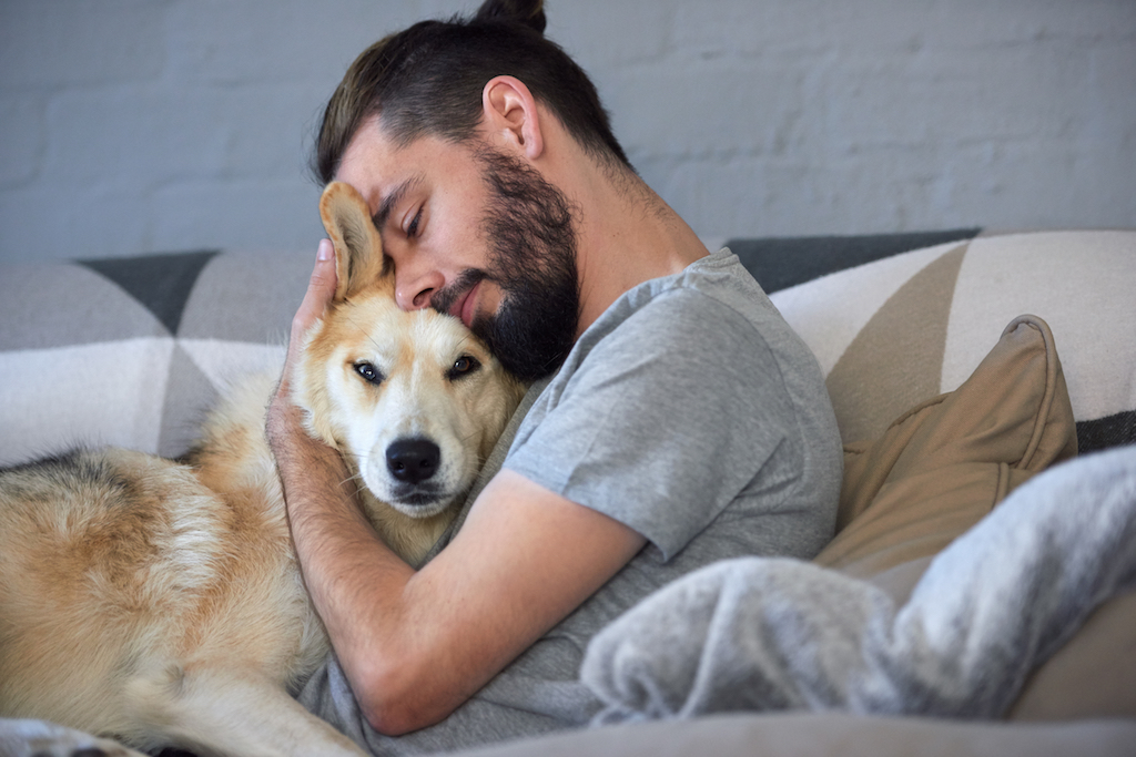 man in bed hugging his dog