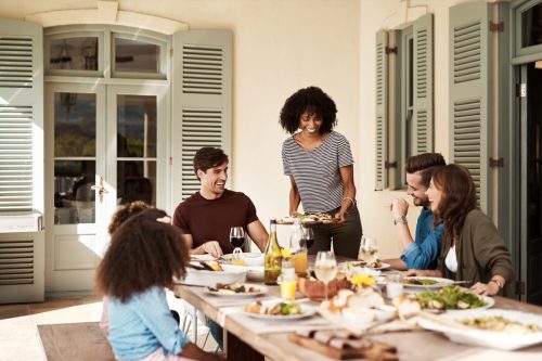 black woman serving food to family and friends at outdoor table
