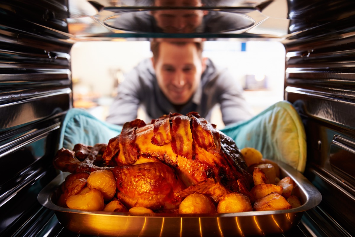 Young man taking turkey out of oven