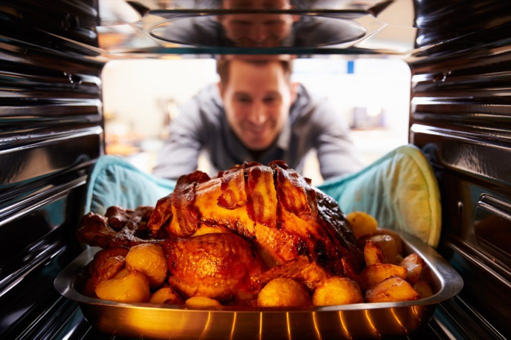 man taking turkey out of oven, worst things about being an empty nester