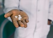 Man holding pills, medication, or vitamins
