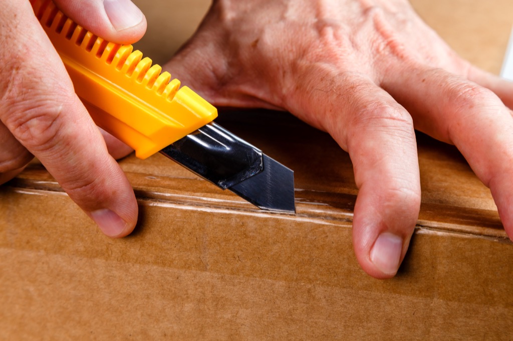 man opening a box with a utility knife