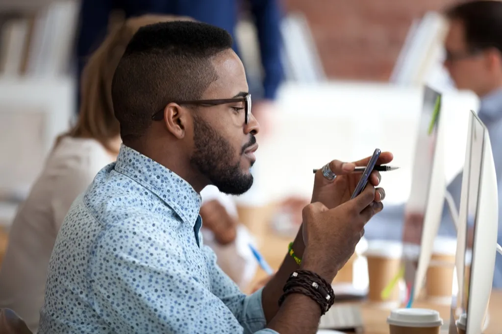 Young Millennial Worker on His Phone Signs of Burnout