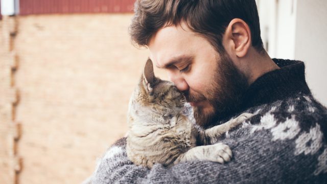 man cuddling his pet cat