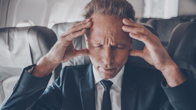 businessman on an airplane suffering the side effects of flying