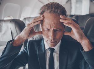 businessman on an airplane suffering the side effects of flying