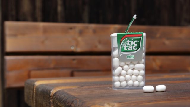 an open mint white tic tac box resting on a wooden table