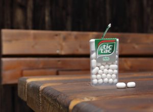 an open mint white tic tac box resting on a wooden table