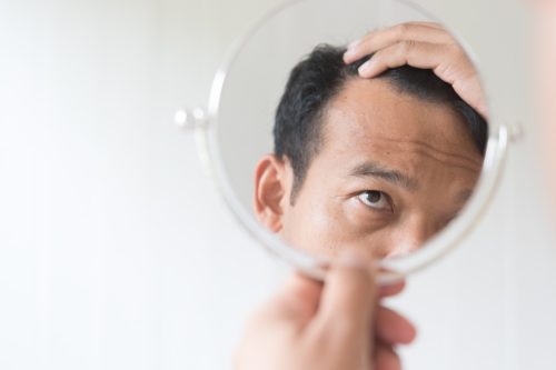 Bătrân care se uită în oglindă la căderea părului regretă peste 50 de ani