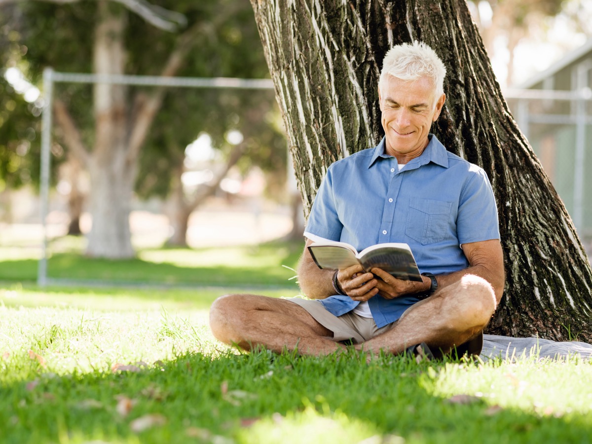 man reading by a tree at the park