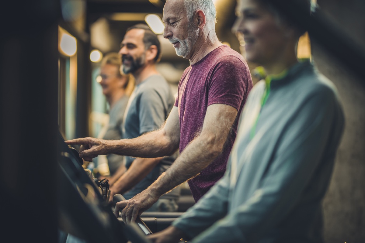 Group of athletic senior exercising on treadmills at the gym