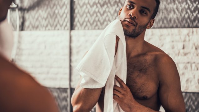 a shirtless man holding a towel looking in the mirror, relationship white lies