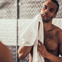 a shirtless man holding a towel looking in the mirror, relationship white lies