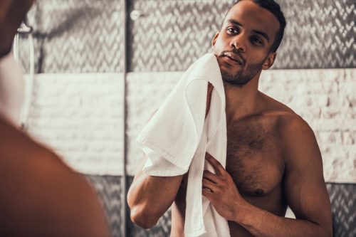 a shirtless man holding a towel looking in the mirror, relationship white lies