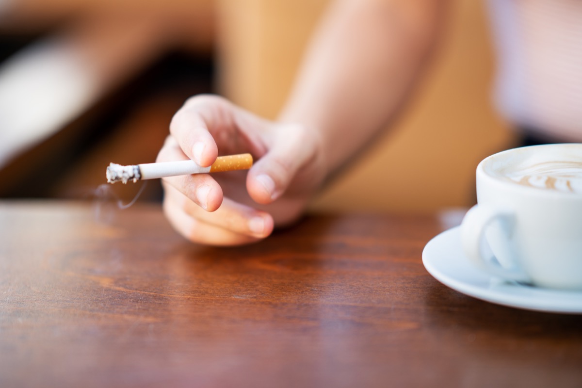 Femeie care fumează în timp ce bea cafea într-o cafenea