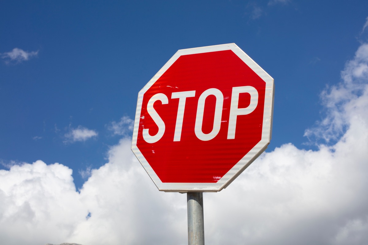 Stop sign against blue sky with clouds
