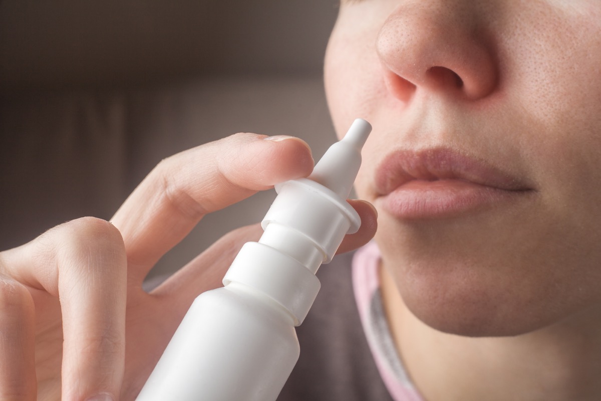 Woman Using Nasal Spray For Her Cold