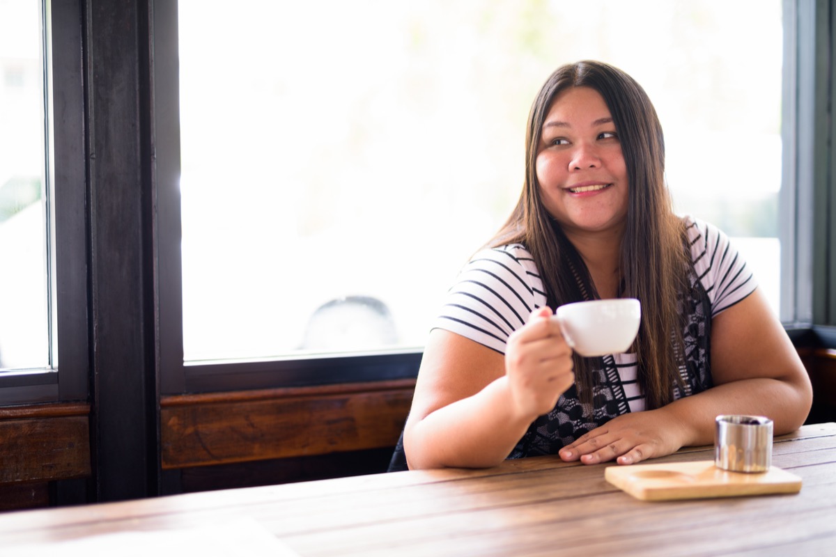 Portrait of beautiful overweight Asian woman relaxing at the coffee shop