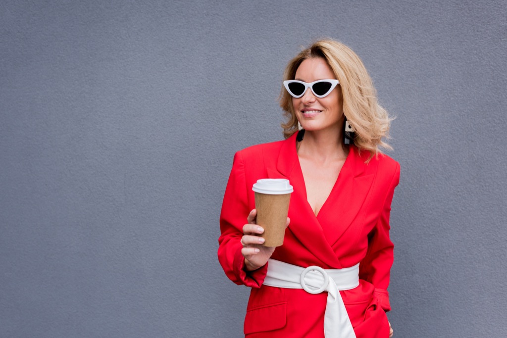 stylishly dressed woman holding a takeout coffee