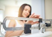 Shot of a young woman weighing herself on a scale